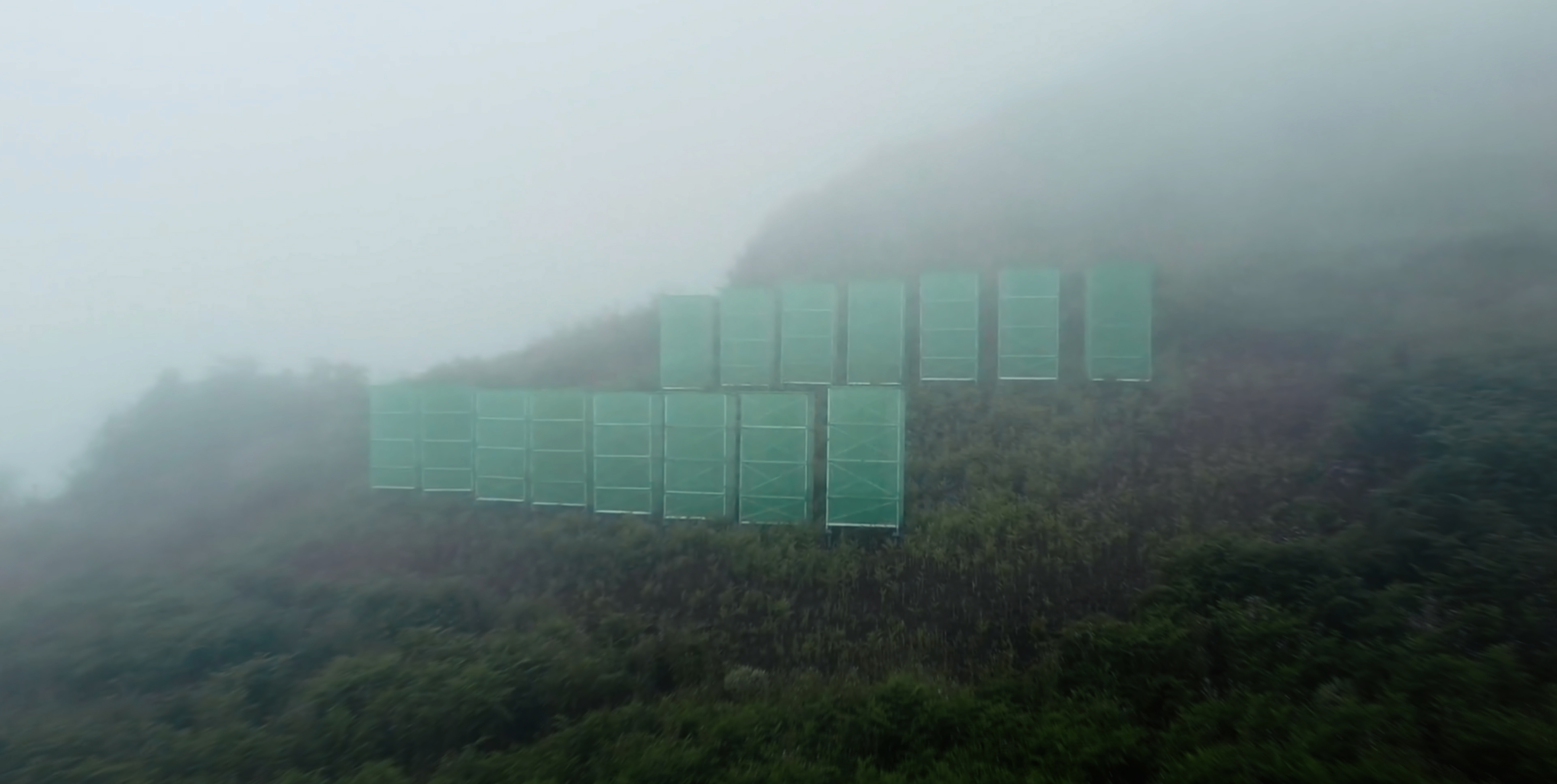 Foggy hills with scaffolding covered in green cloth