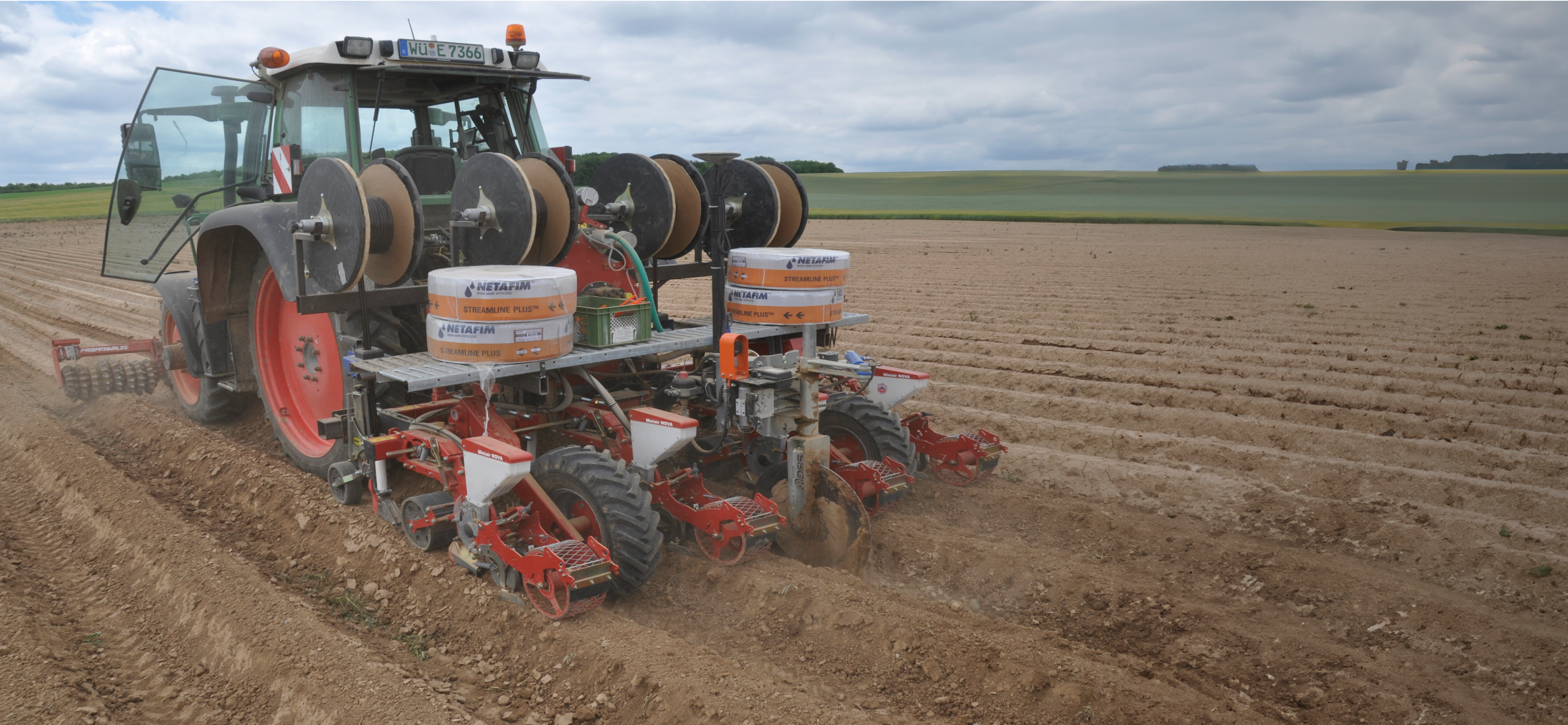 A tractor laying watering hoses on a field near Würzburg