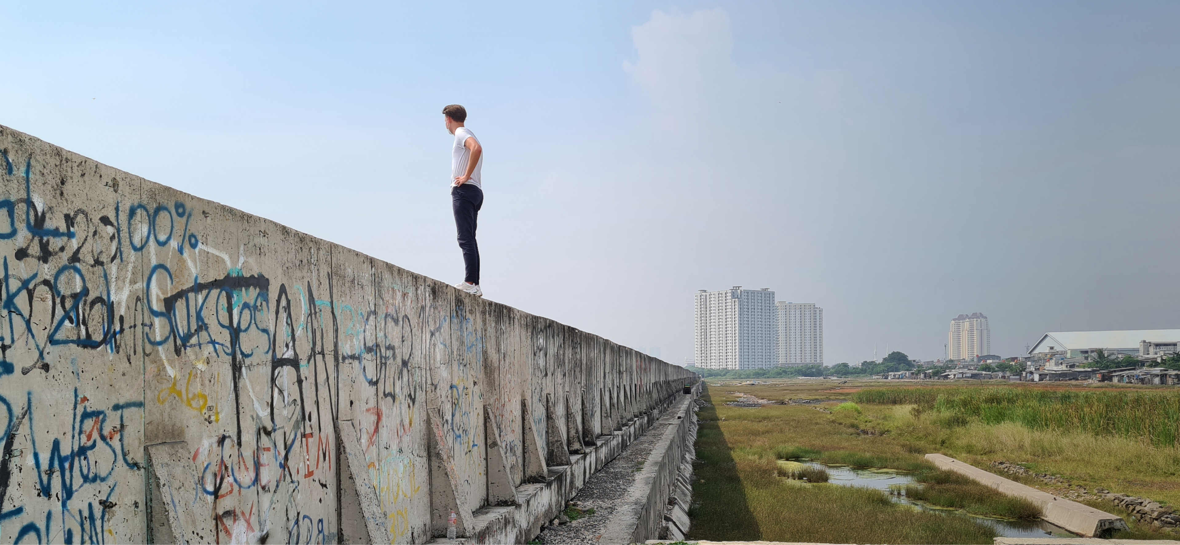 Man standing on graffitied flood wall