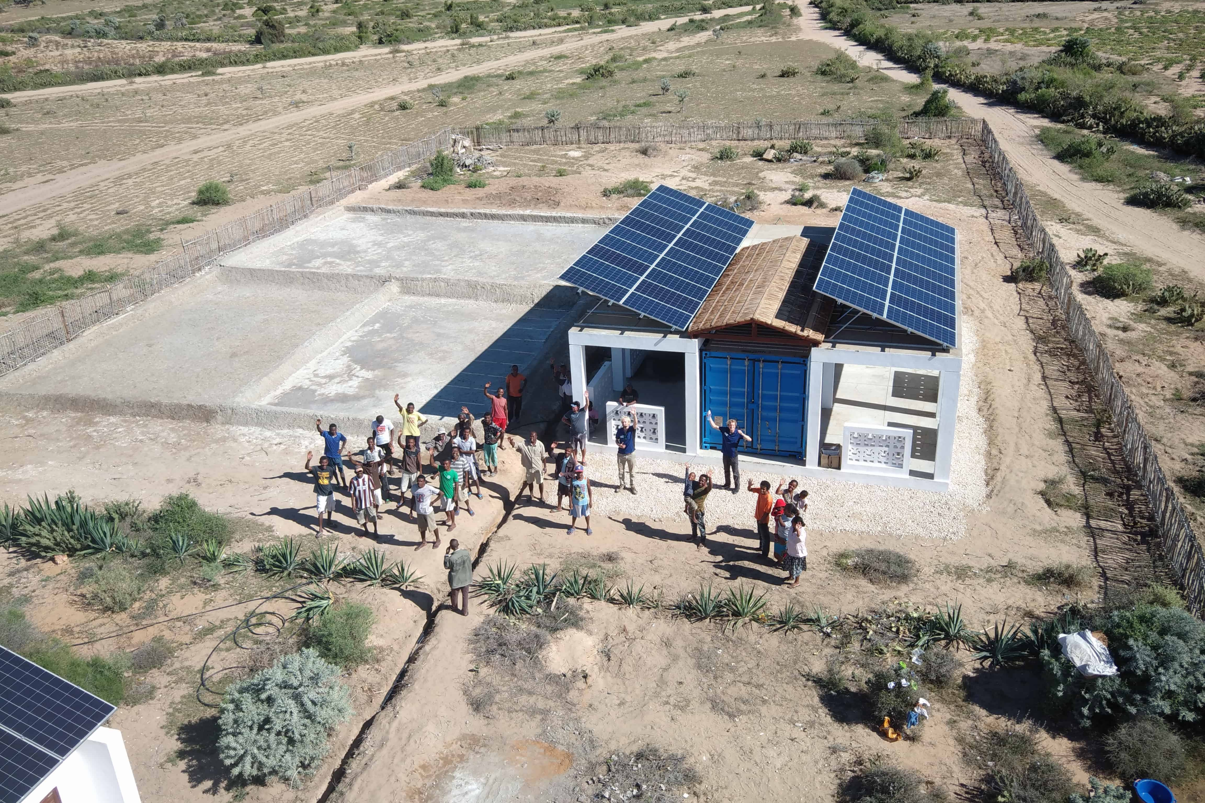 Aerial shot of a group of people in front of solar panel
