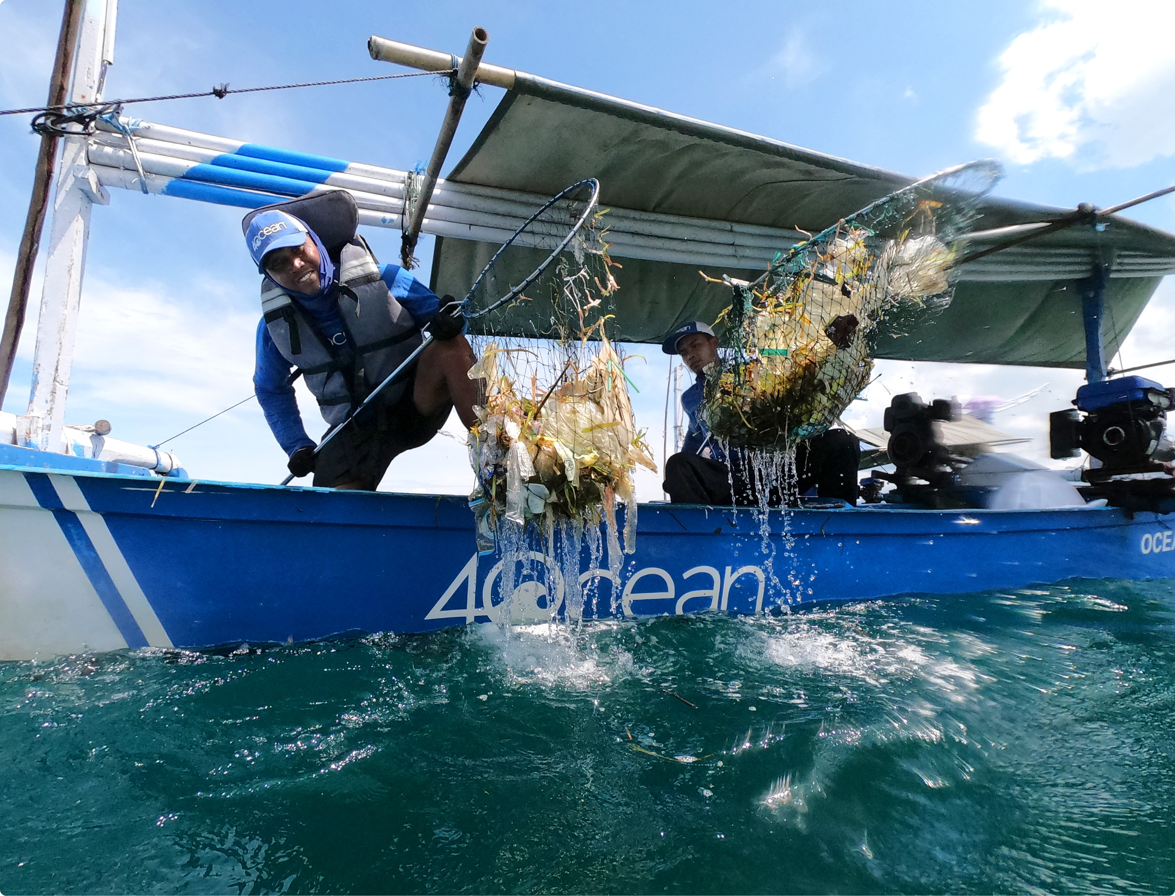 Two 4ocean volunteers lifting trash from the ocean with a net.