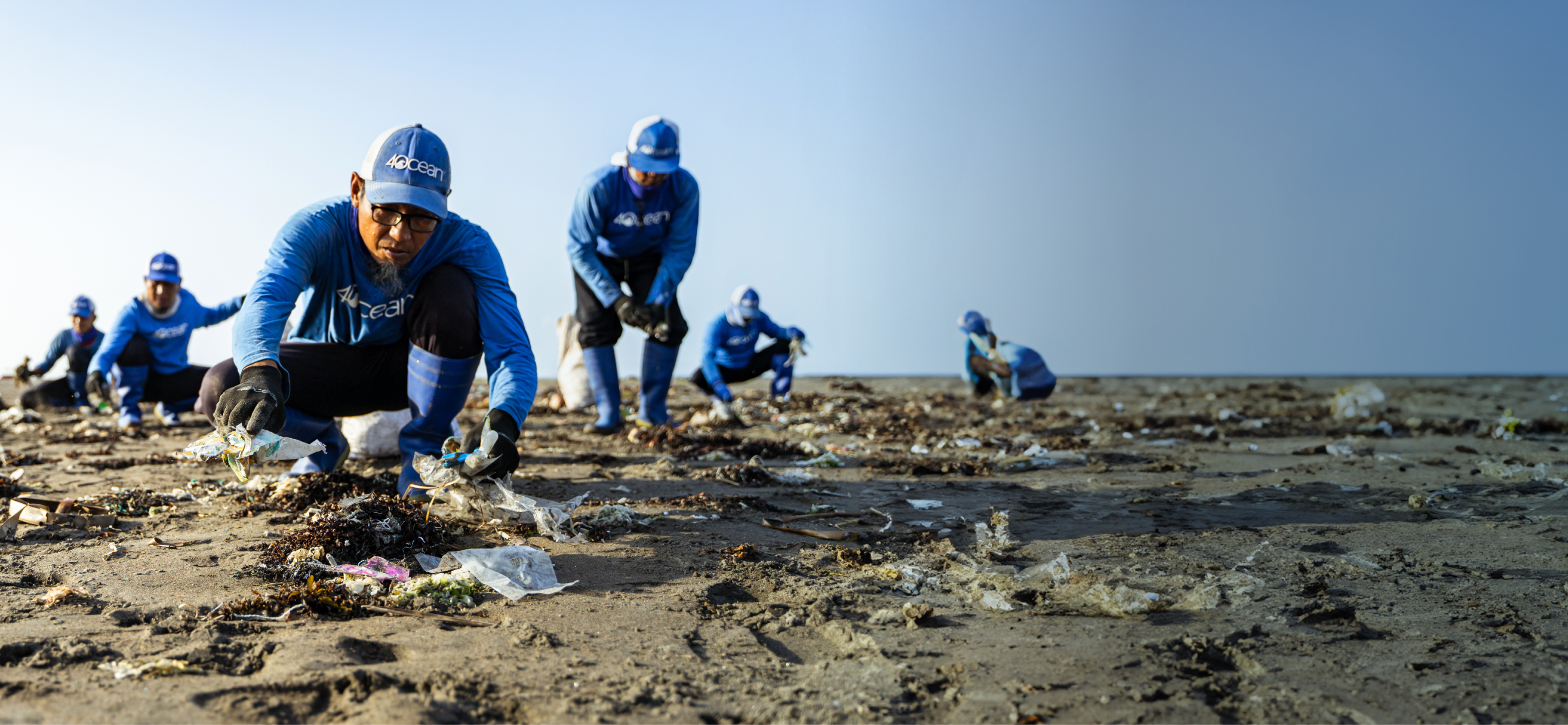 4ocean volunteers picking up trash at the beach.